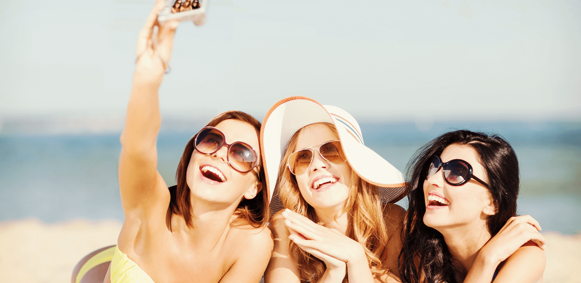 teens take a selfie on the beach, showing their tartar vs plaque free smiles