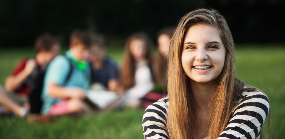 adolescent smiling on lawn with braces