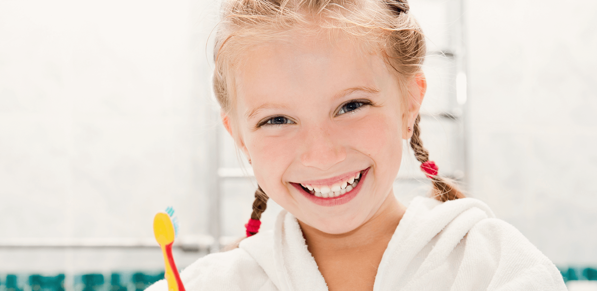young child smiling holding toothbrush