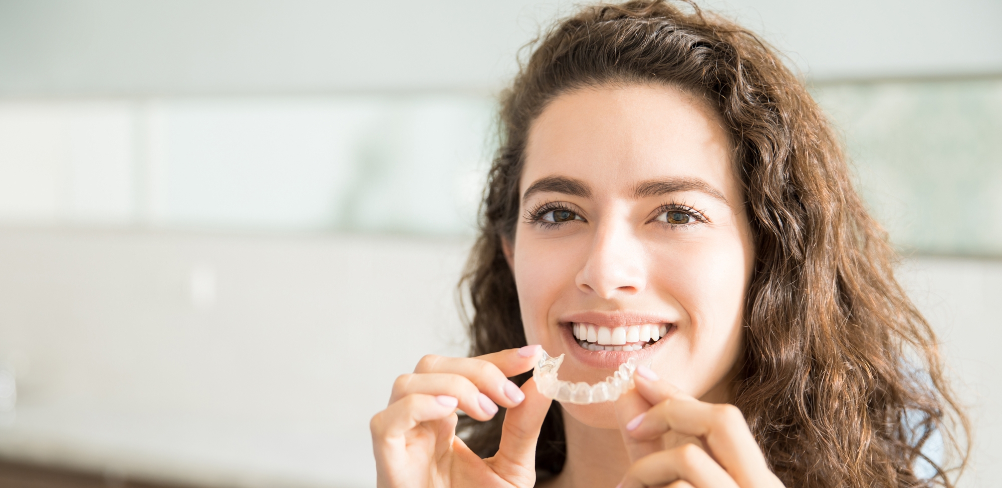 young woman smiling while holding invisalign treatment
