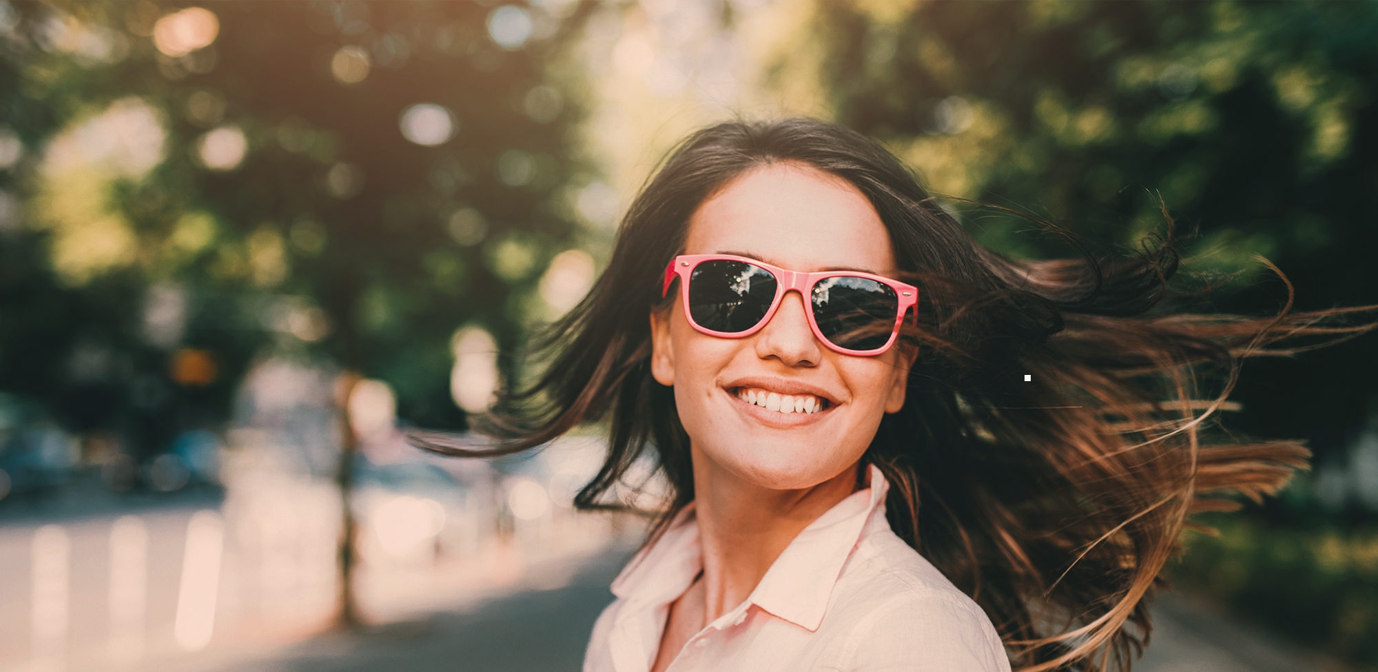 young woman smiling while wearing sunglasses