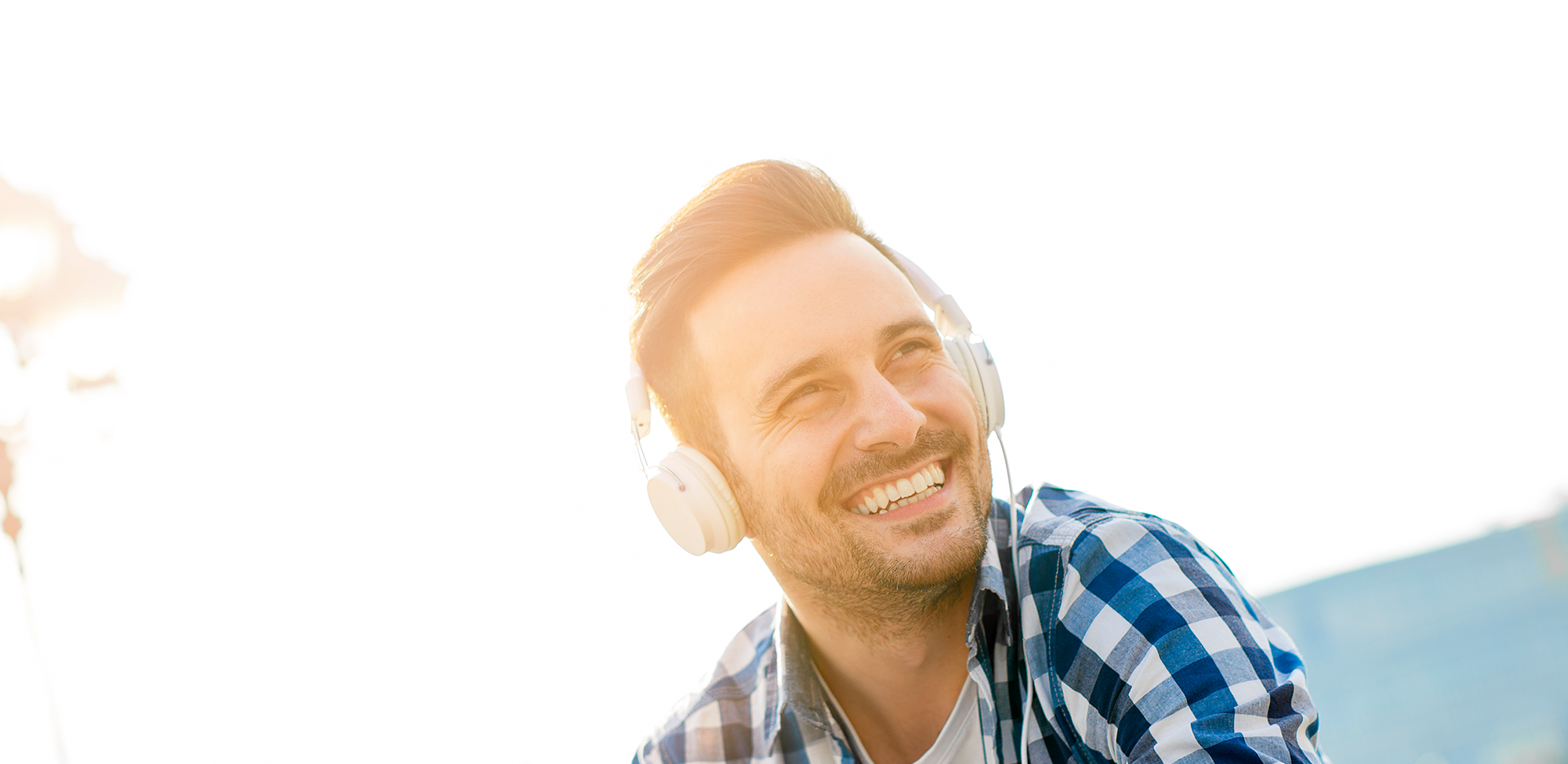 A man wearing headphones, listening to music and smiling