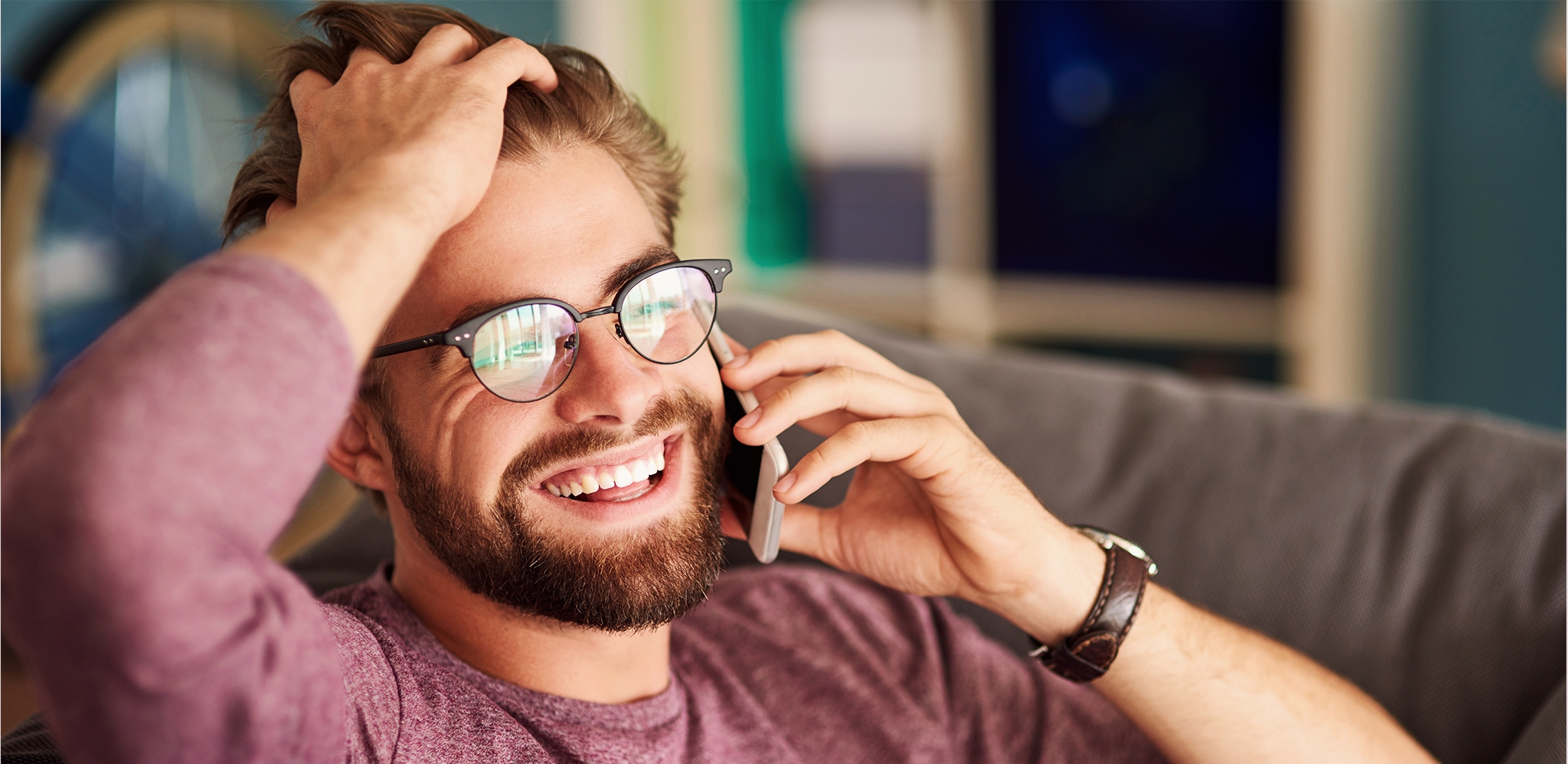 young man smiling while talking on the phone