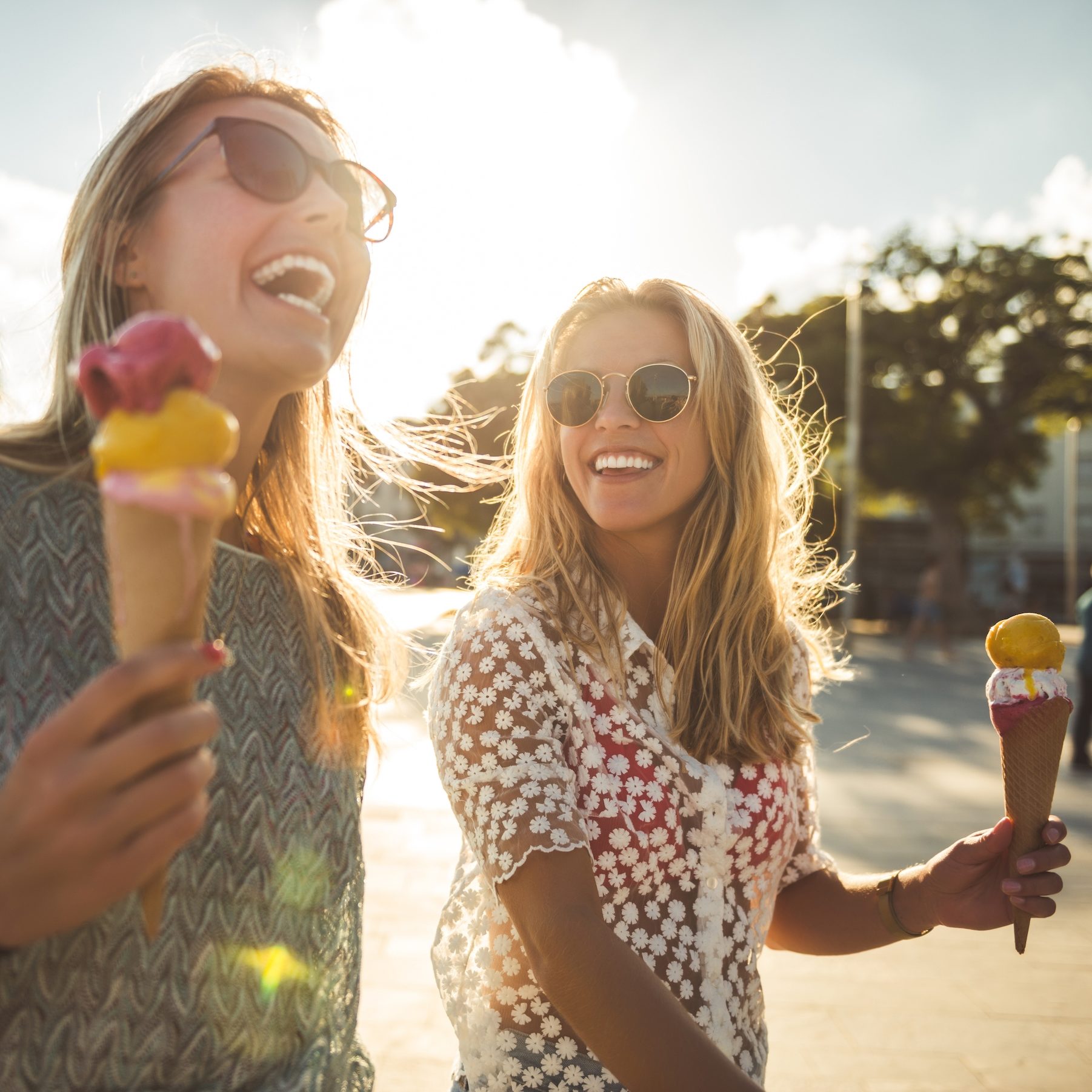 Two teens holding cones of ice creams, smiling and enjoying their day