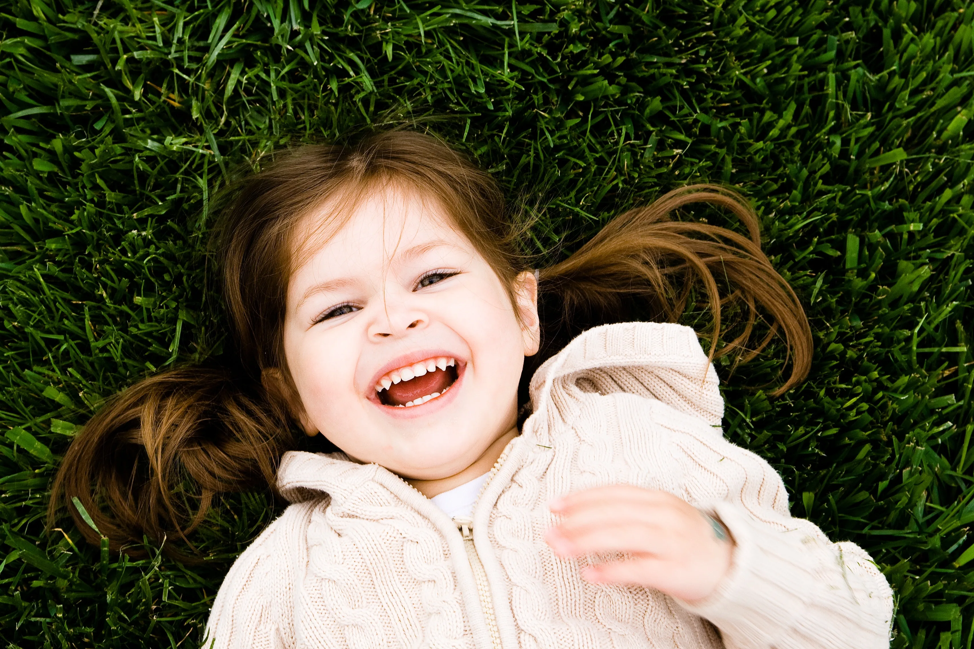 young girl smiling while laying in the grass