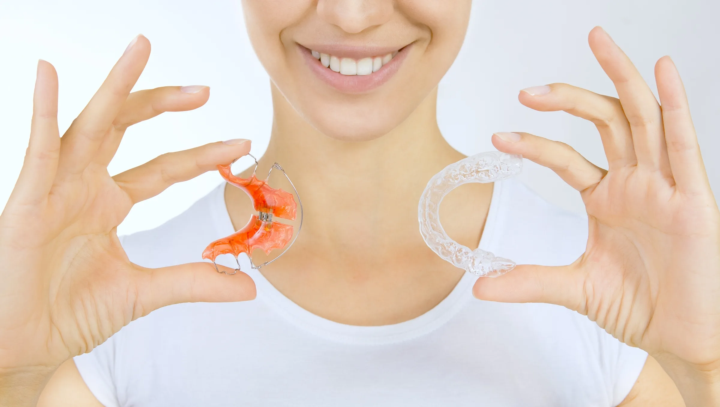 A woman holding two types of retainer on both of her hands