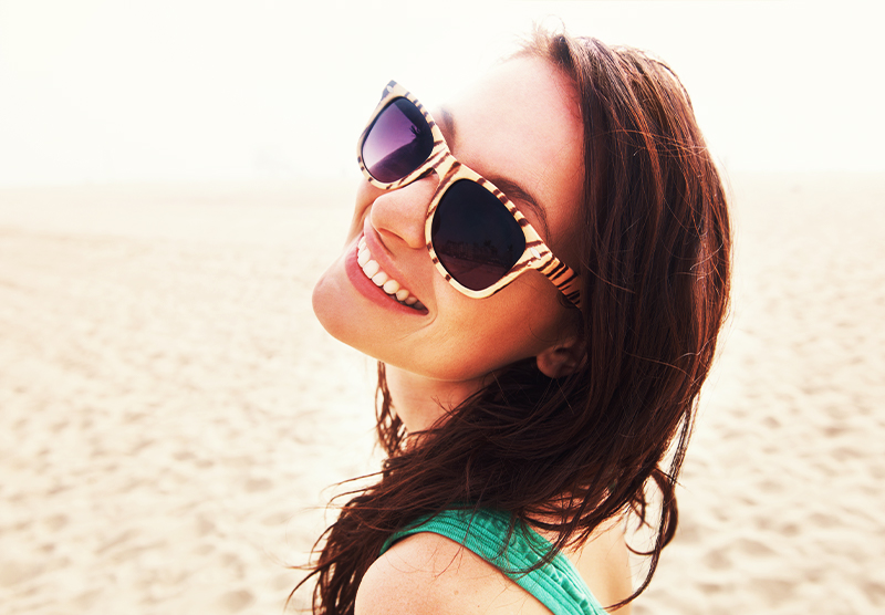 Young girl smiling on beach with Invisalign at Caudill & McNeight Orthodontics, How Braces Work