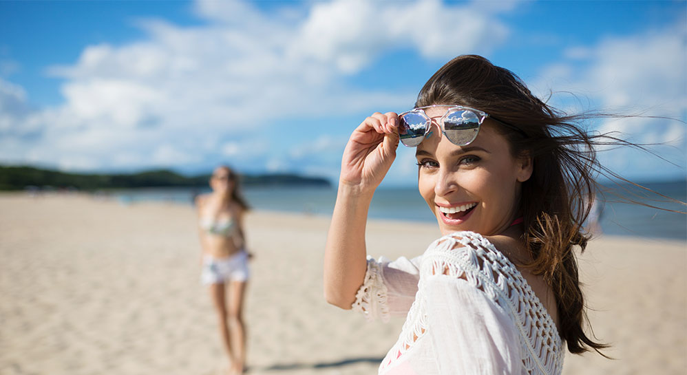Women smiling at the beach while wearing Invisalign.