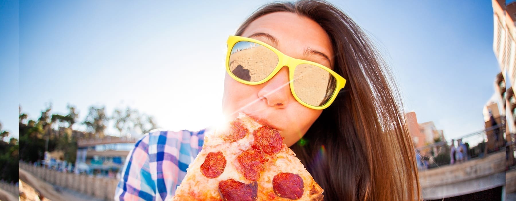 Girl in city eating pizza with sunglasses