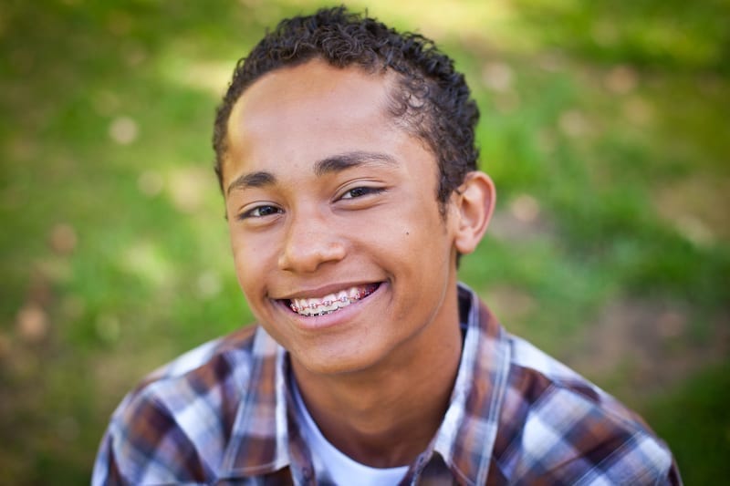 Young Male Teen with braces smiling at the camera.