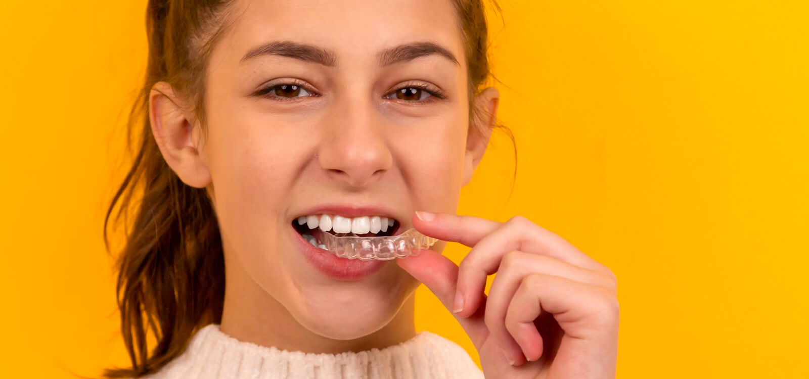 teen holds aligner to teeth and learns Invisalign tips
