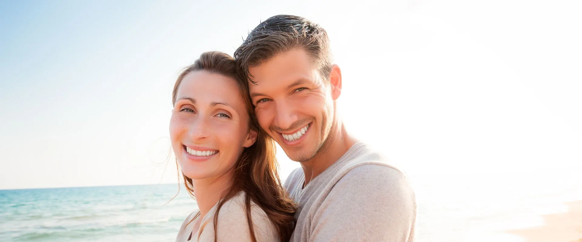 husband and wife walk the beach and read Invisalign FAQs